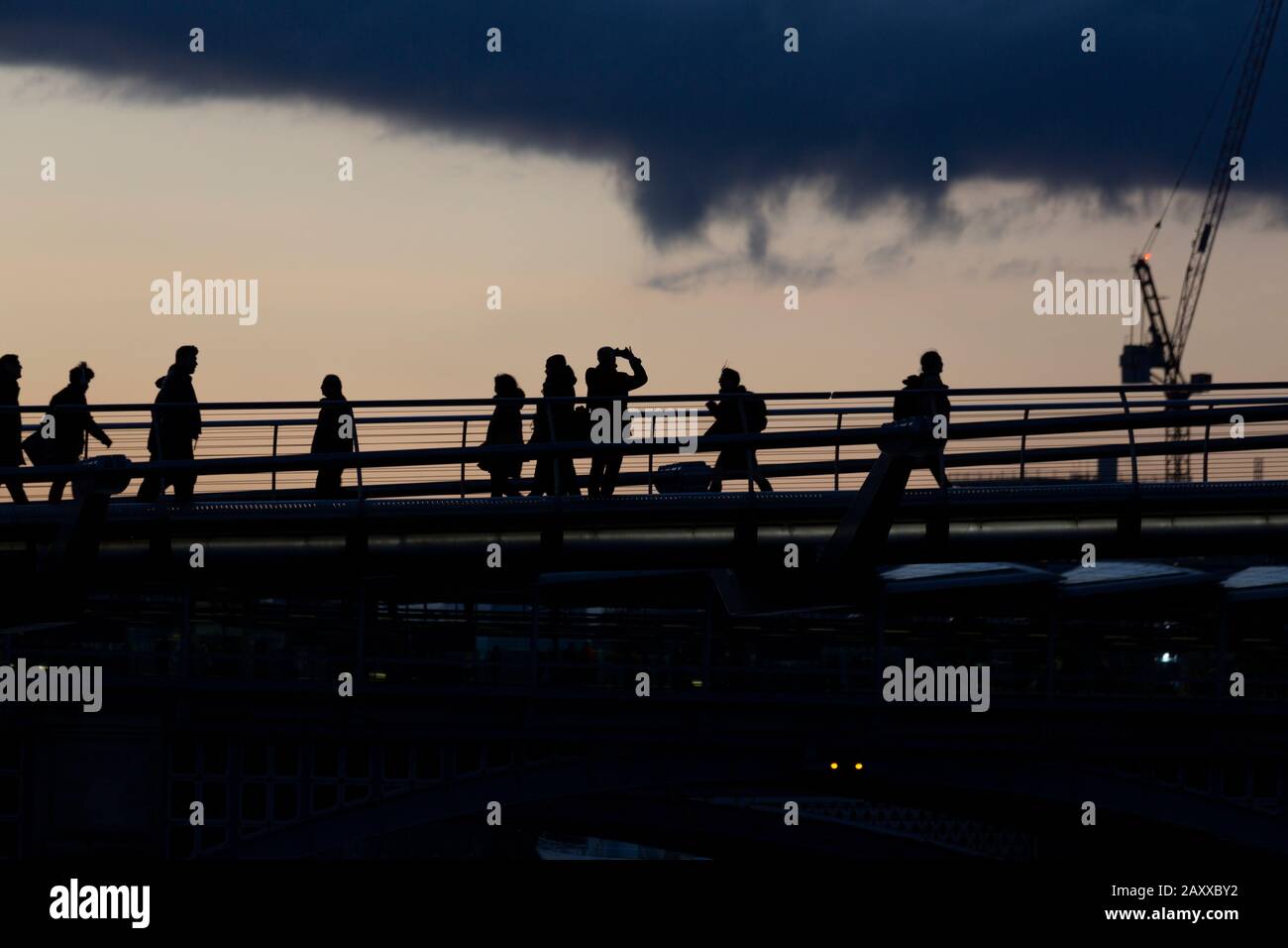 Londres, Royaume-Uni. 13 février 2020. Coucher du soleil, un passage de banlieue Millennium Bridge s'arrête pour prendre une photo regardant vers l'ouest le long de la Tamise pendant la marée haute du printemps. Crédit: Thamesfleet/Alay Live News Banque D'Images