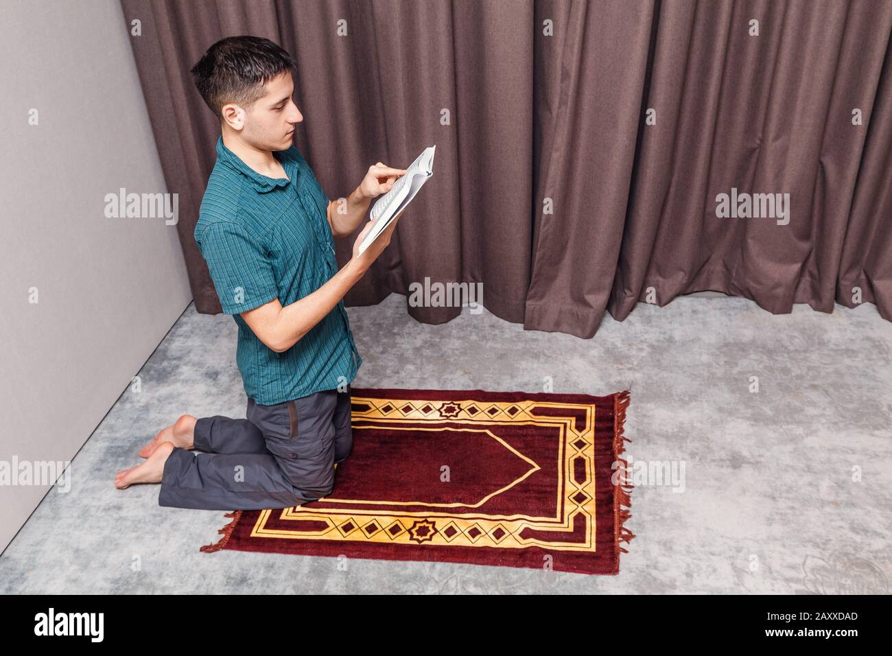 Un jeune homme prie et récite le coran musulman sur un petit tapis portable  à l'intérieur. Religion et concept rituel Photo Stock - Alamy