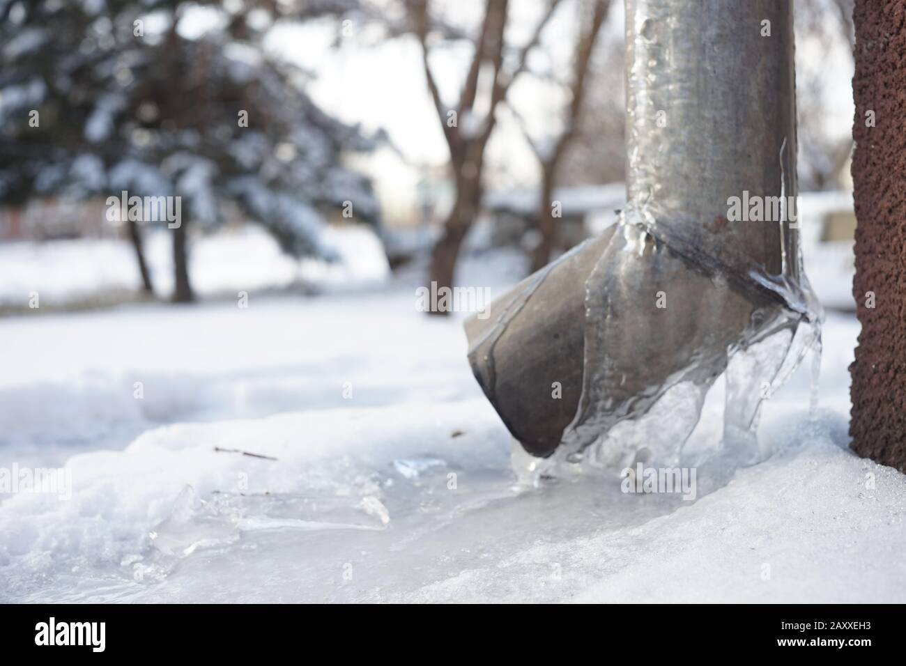 Drainpipe recouvert de glace à l'angle de la maison. Banque D'Images