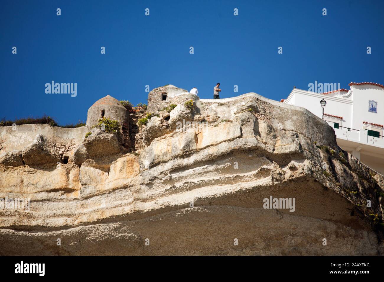 Le quartier de Sitio est situé sur des falaises abruptes. L'homme se tenant sur une falaise au-dessus des ouvertures de tir surplombe la mer et la plage de Praia. Banque D'Images