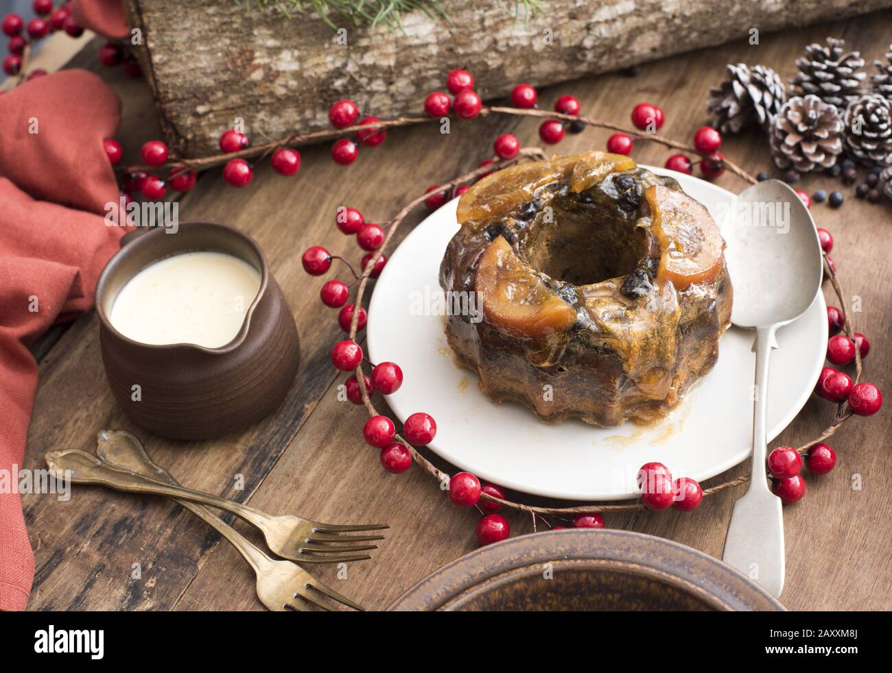 Délicieux pudding aux prunes de Noël maison avec sauce au brandy et baies rouges festives colorées sur la table Banque D'Images