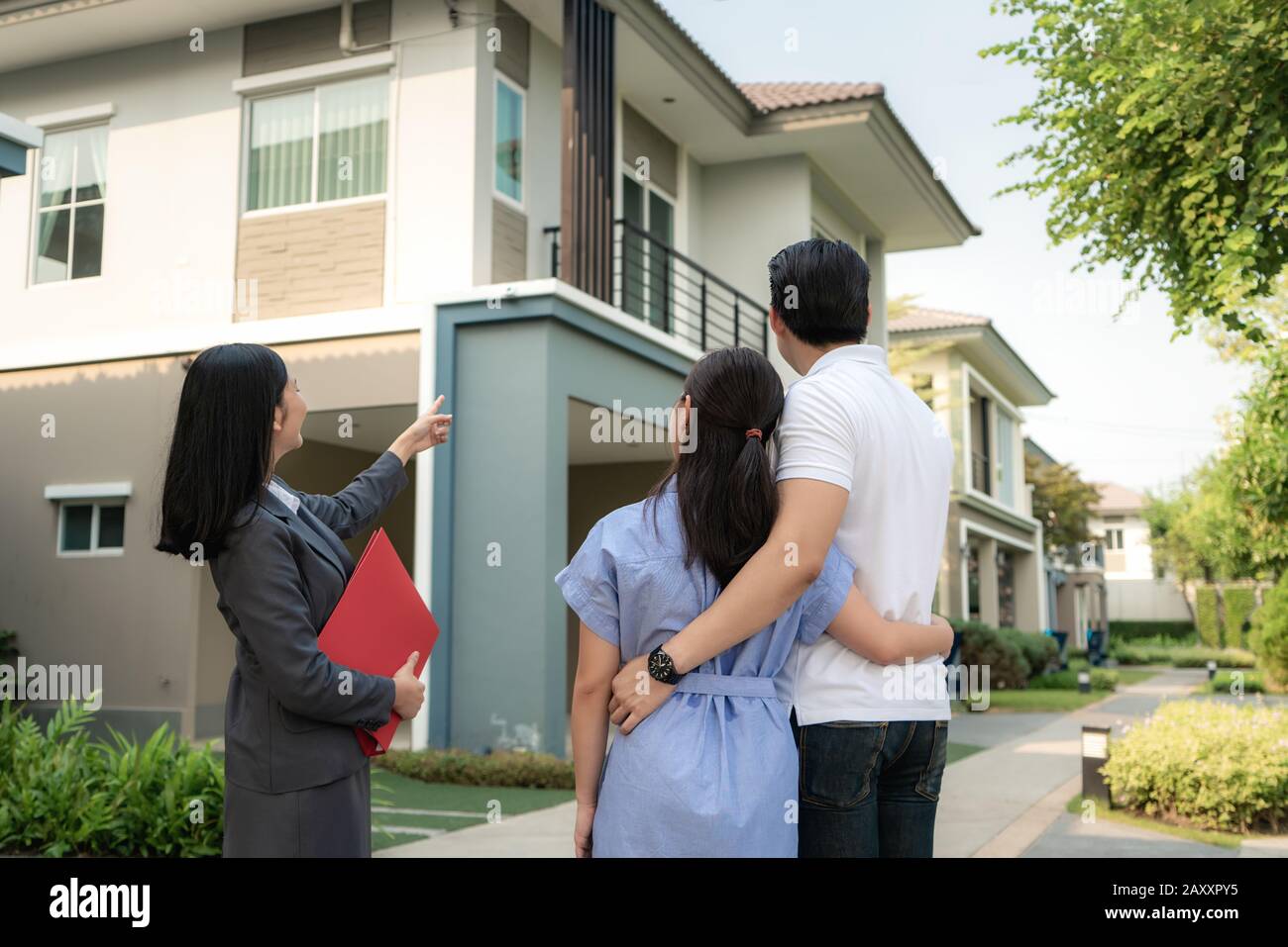 Agent immobilier de femme asiatique montrant un détail de projet de maison dans son dossier à la jeune couple asiatique amoureux recherchant et intérêt à l'acheter. Achat Banque D'Images