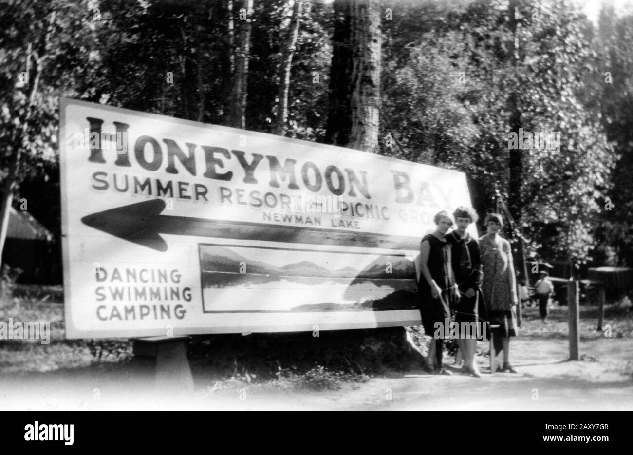 Trois jeunes femmes posent devant un panneau de station dans l'État de Washington, ca. 1930. Banque D'Images