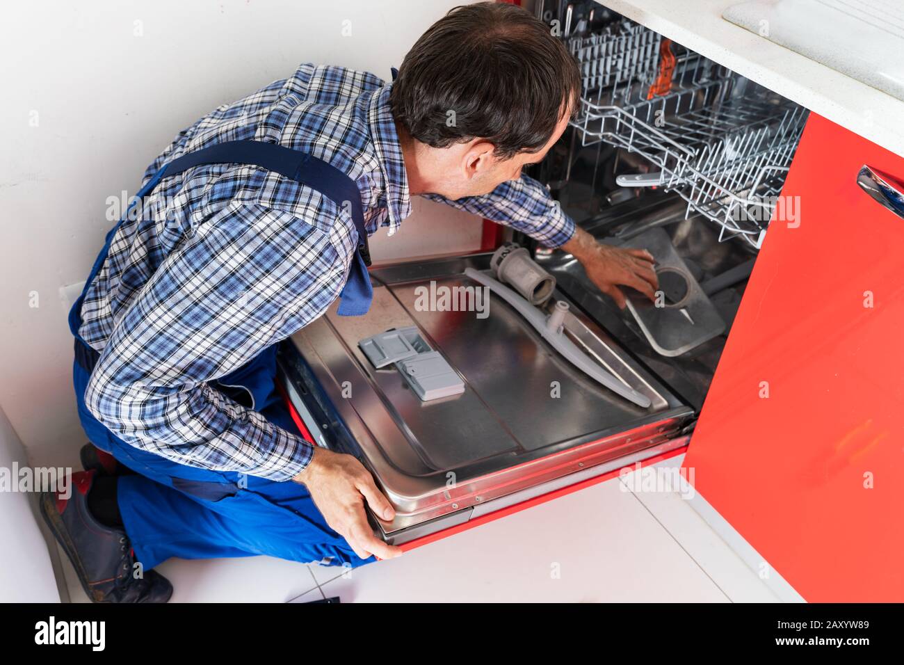 Photo Du Réparateur Examinant Le Lave-Vaisselle Dans La Cuisine Banque D'Images
