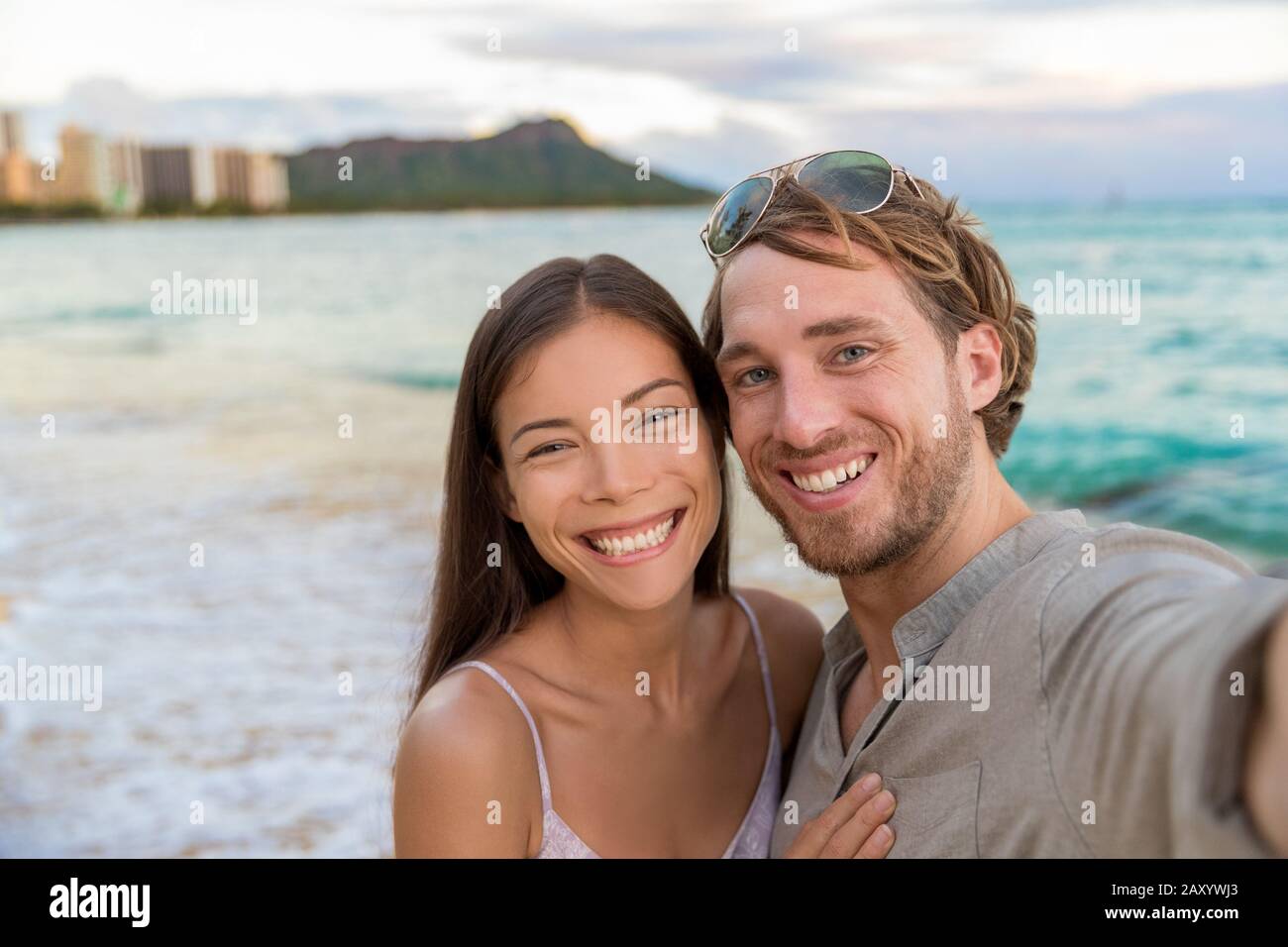 Couple selfie sur la plage de Waikiki prenant des photos avec smartphone pendant la nuit dehors marcher sur la plage vacances d'été à Honolulu, Hawaï. Destination de voyage. Les jeunes s'amusent pendant les vacances hawaïennes. Banque D'Images