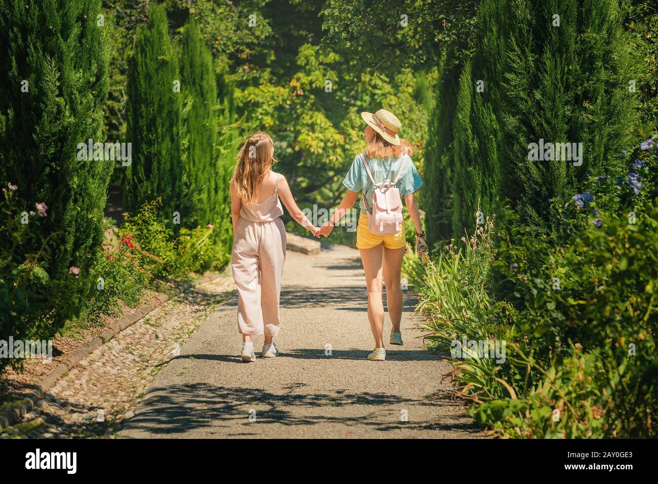 Happy girl amis marchant par un chemin dans le parc local parmi les arbres à la journée d'été Banque D'Images