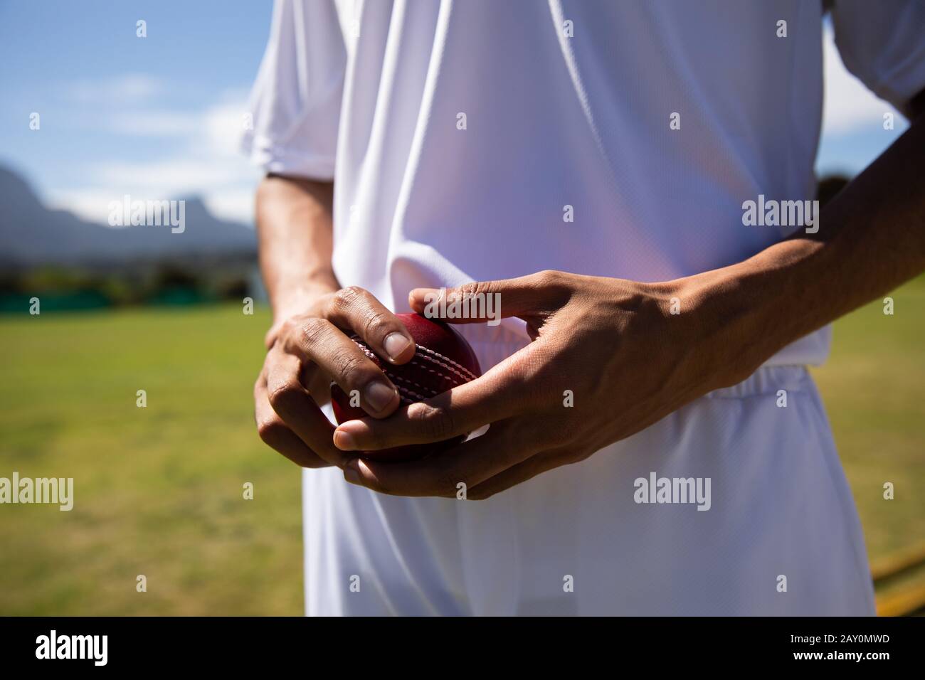 Joueur de cricket debout et tenant un ballon Banque D'Images