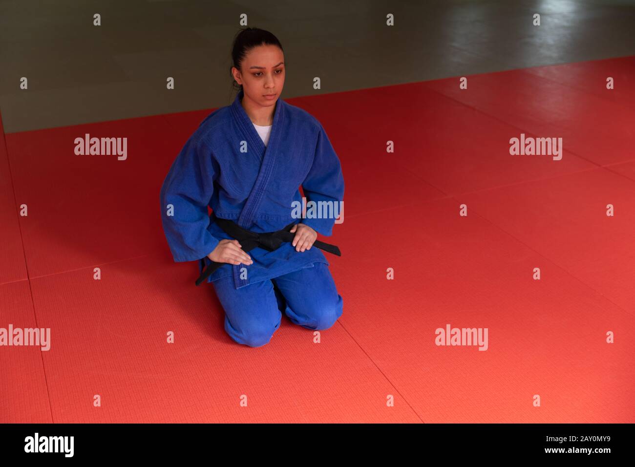Judoka s'agenouillant sur des tapis dans la salle de gym avant de s'entraîner à judo Banque D'Images