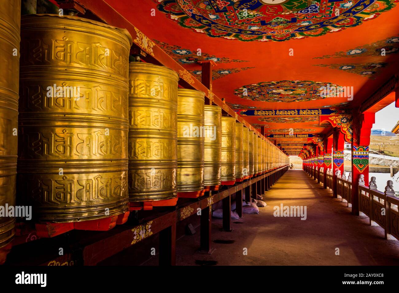 Roues de prière bordant le long couloir d'une structure de temple tibétain Banque D'Images