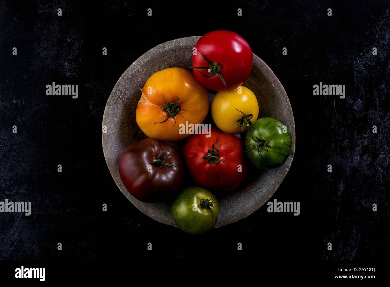 Grand angle gros plan de la plaque grise avec sélection de tomates dans différentes formes et couleurs sur fond noir. Banque D'Images