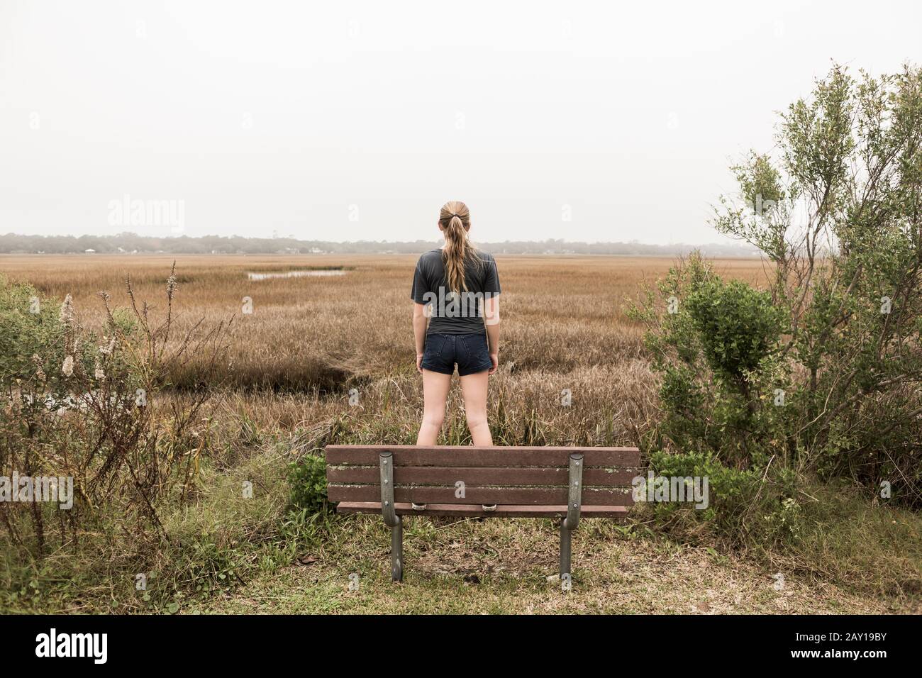 Une adolescente se tenant sur un banc qui regarde les marais, l'île de Saint-Simon, Géorgie Banque D'Images