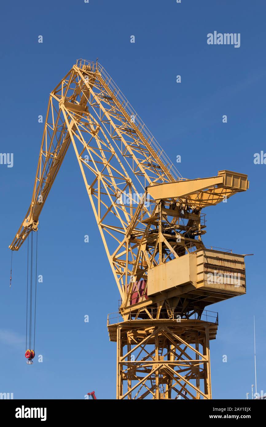 Une énorme grue en métal jaune qui travaille de jour dans les chantiers navals du Port de Cadix, Andalousie, Espagne, près de l'avenue Astilleros Banque D'Images
