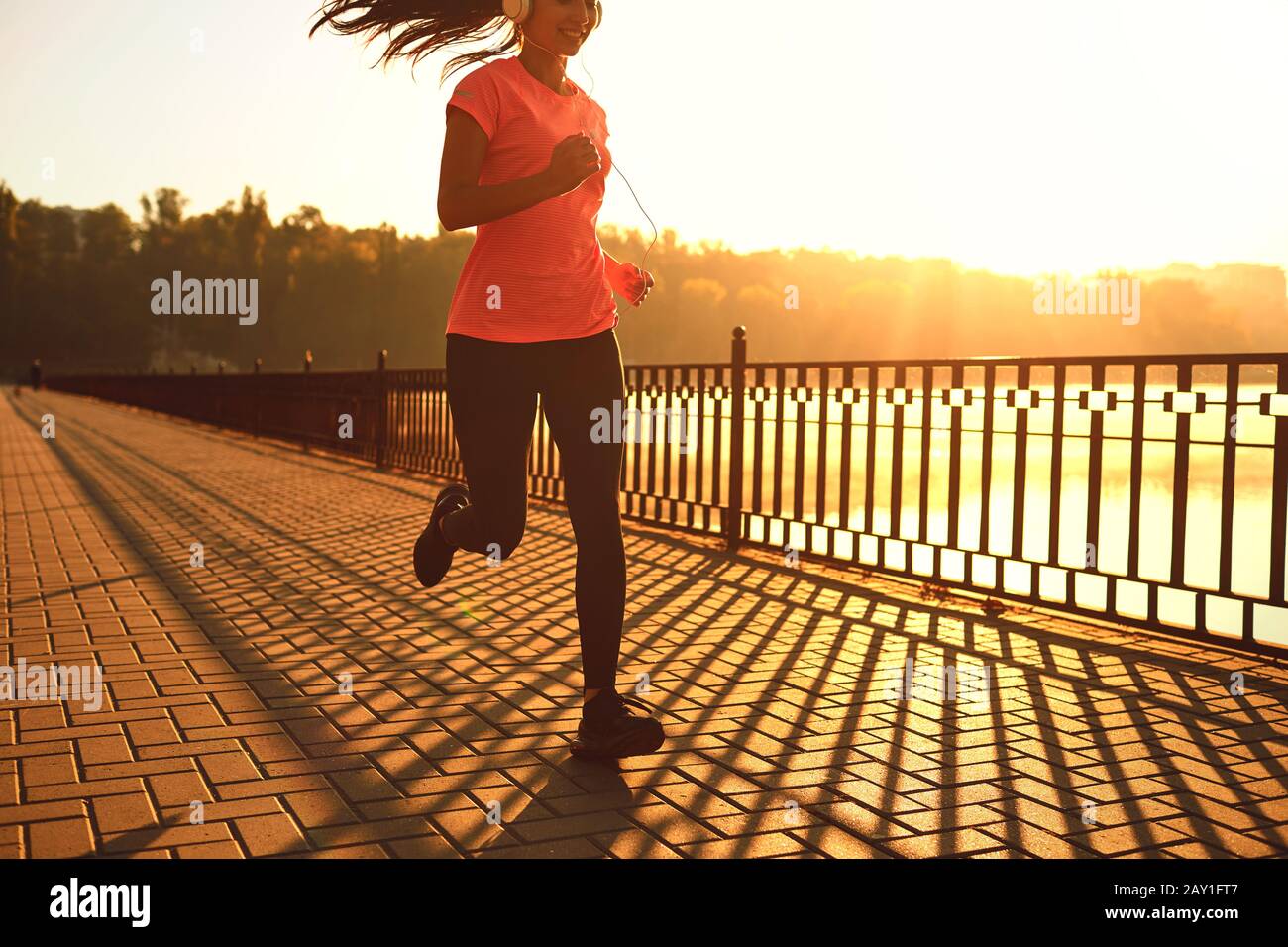 Runner fonctionne sur la route dans le soleil au coucher du soleil dans un parc en automne. Banque D'Images