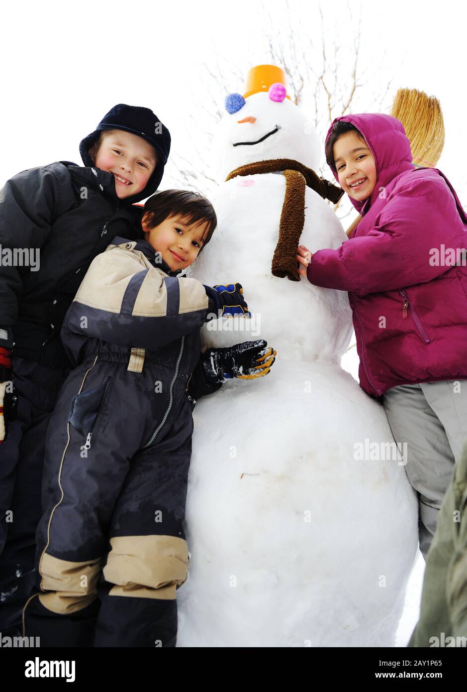 Les enfants jouent avec joie dans la neige en faisant du bonhomme de neige, saison d'hiver Banque D'Images