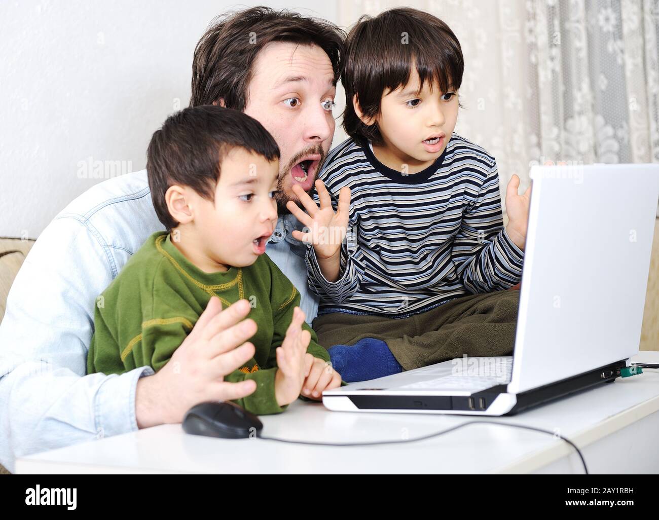 Family in living room with laptop smiling Banque D'Images