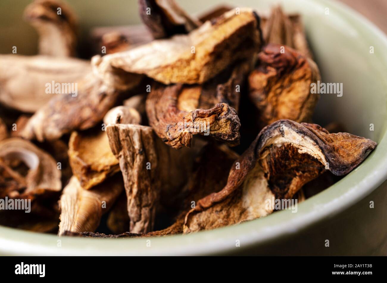 Gros plan (macro) de champignons porcini séchés empilés dans un bol en céramique verte. Banque D'Images