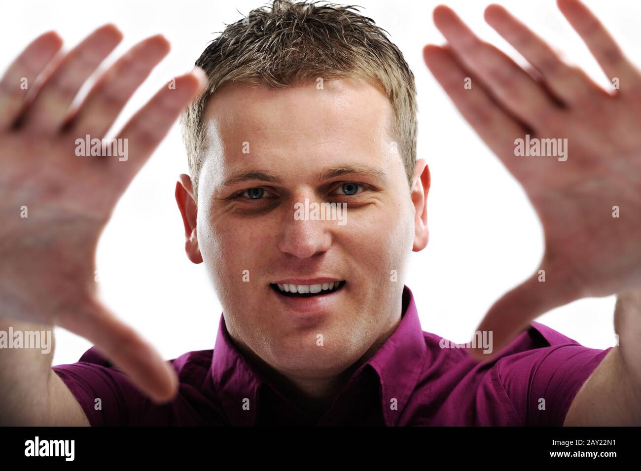Portrait de l'homme souriant faisant le cadre avec les mains sur fond blanc Banque D'Images