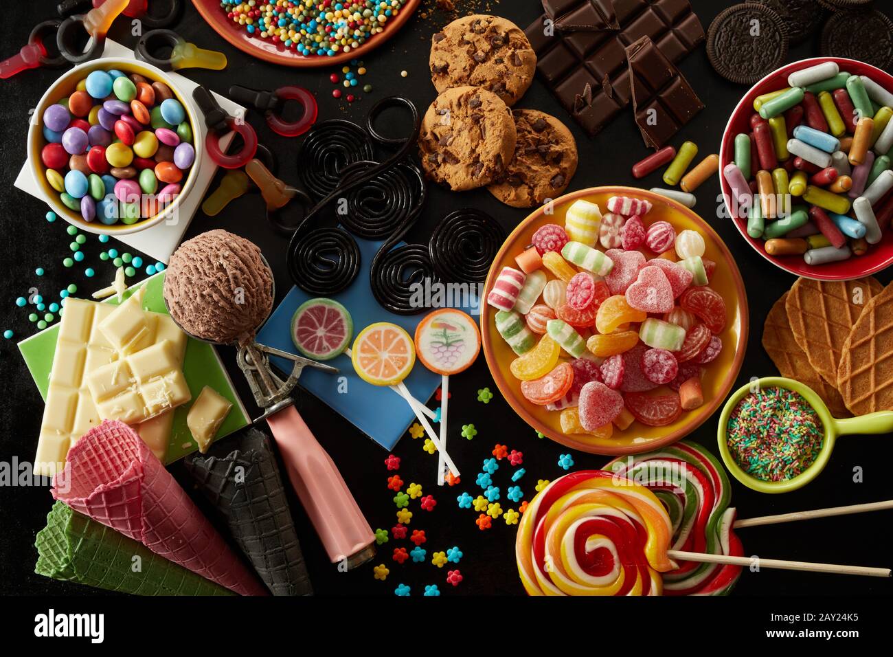 Sélection de friandises de fête pour un anniversaire pour enfants avec assortiment de bonbons, crème glacée, biscuits, biscuits, barres de chocolat, saupoudrer et sucettes dans un peu plus Banque D'Images