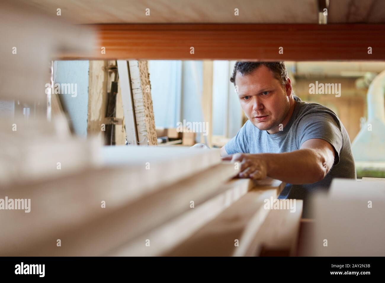 Carpenter en tant que travailleur du bois dans l'entrepôt de menuiserie est à la recherche de bois pour la construction de meubles Banque D'Images