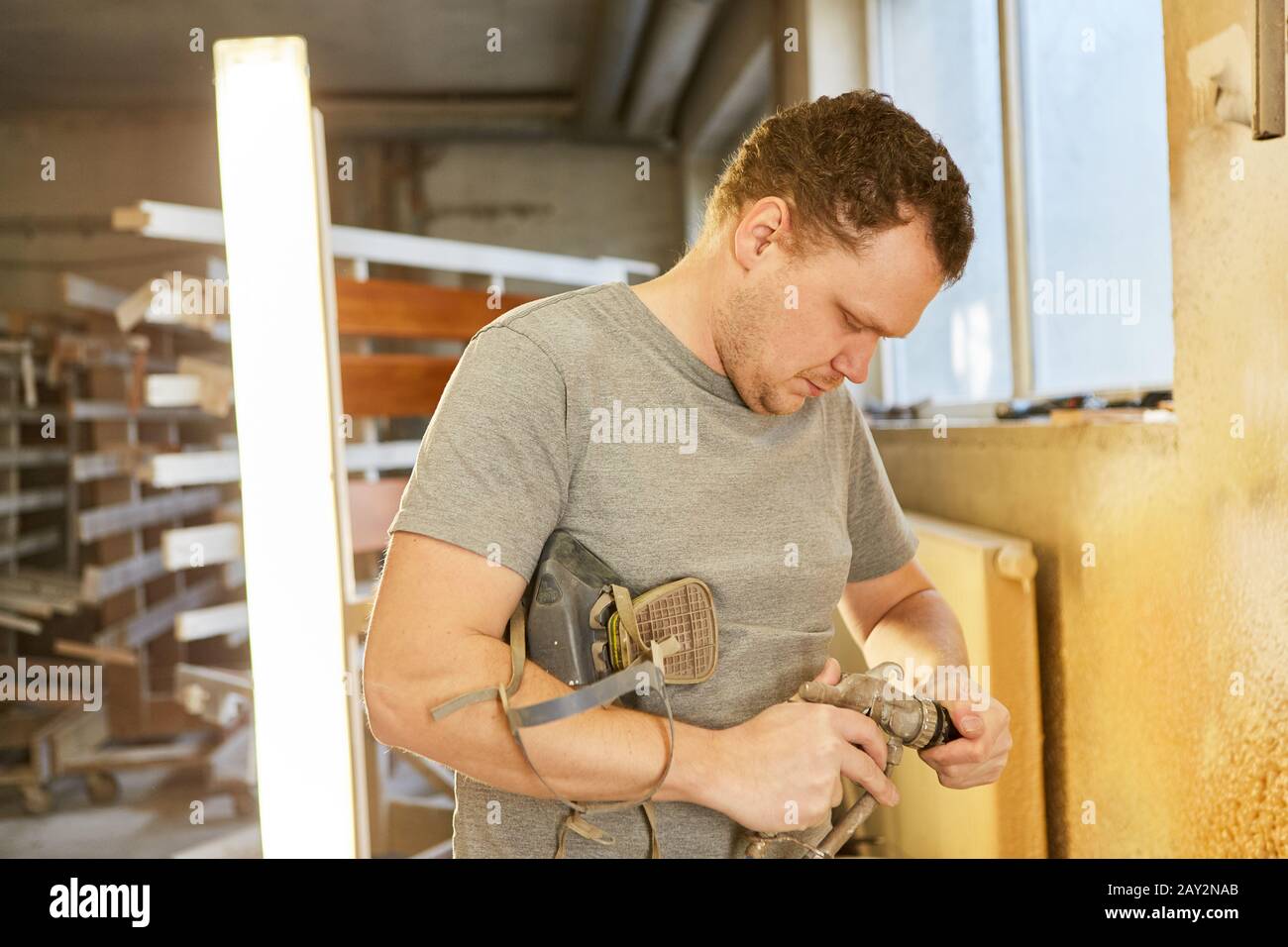 Carpenter comme peintre nettoie la buse de son pistolet dans l'atelier Banque D'Images