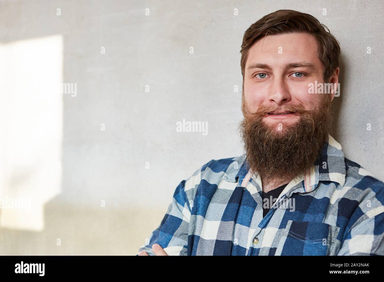Jeune homme taille souriant avec une barbe complète en tant que travailleur ou homme de main Banque D'Images