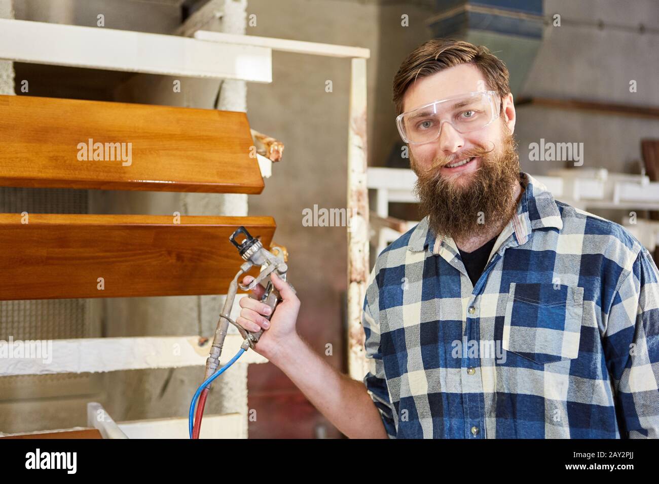 Carpenter en tant que peintre avec le pistolet de pulvérisation dans la menuiserie ou le magasin de peinture Banque D'Images