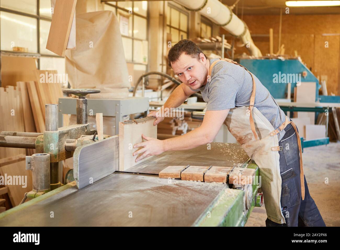 Carpenter apprenti travaille avec la planche en bois sur la machine de planage dans l'atelier de menuiserie Banque D'Images