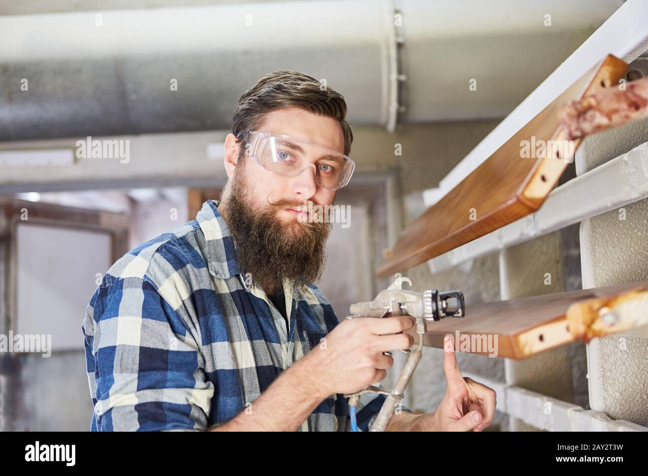 Carpenter comme fabricant de meubles ou peintre lors de la peinture du bois avec un pistolet Banque D'Images