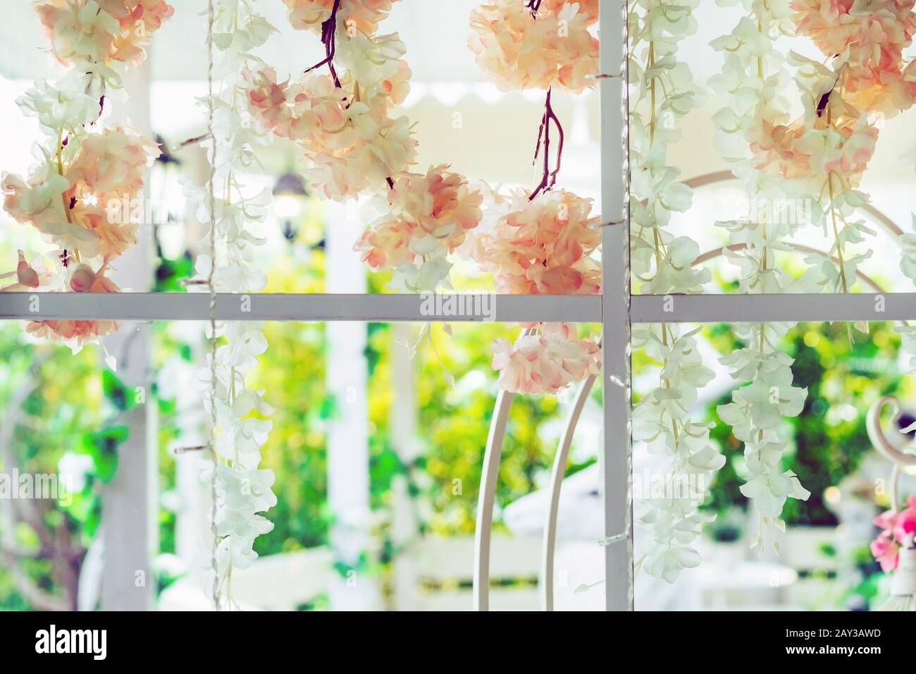 Belles fleurs artificielles accrochées sur des fenêtres en verre pour décorer pour une fête de jardin. Vue depuis la fenêtre sur la vitre. Banque D'Images
