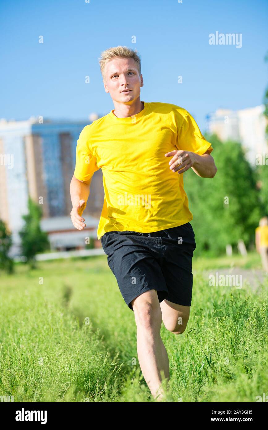 Sporty man jogging in city street park. Remise en forme en plein air. Banque D'Images