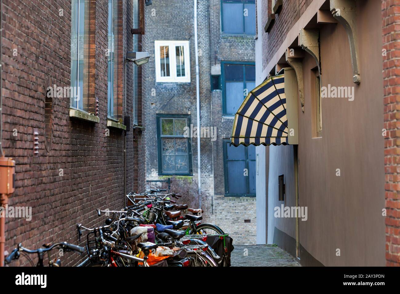 Ancienne petite rue ancienne avec vélos garés et une entrée latérale avec auvent à Dordrecht aux Pays-Bas Banque D'Images