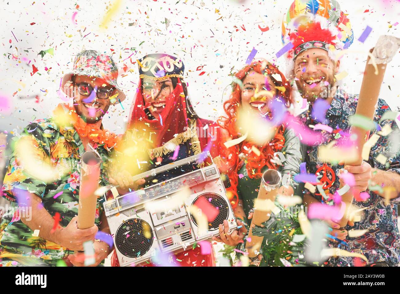 Joyeux amis célébrant l'événement de fête de carnaval en plein air - jeunes fous ayant des costumes amusants à écouter de la musique avec une chaîne stéréo vintage boombox Banque D'Images