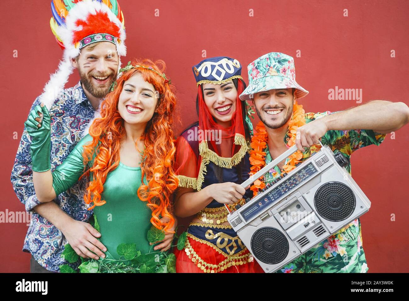 Heureux amis célébrant la fête du carnaval en plein air - jeunes fous ayant des costumes de fantaisie écoutant de la musique avec la chaîne stéréo vintage boombox Banque D'Images