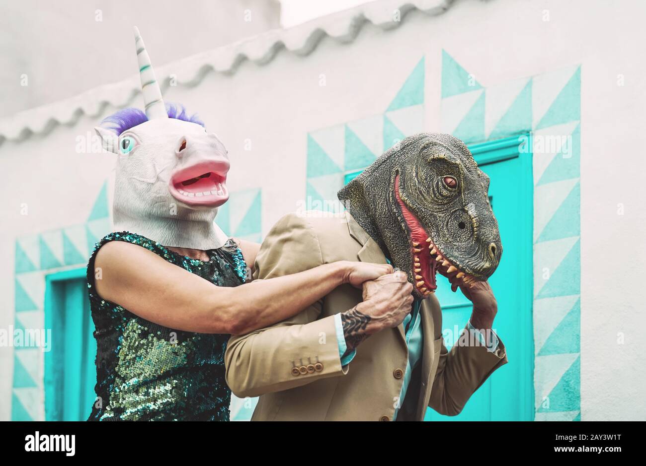 Couple senior fou portant le masque unicorn et t-rex tout en dansant en plein air - personnes à la mode mûre ayant plaisir à célébrer le temps du carnaval Banque D'Images
