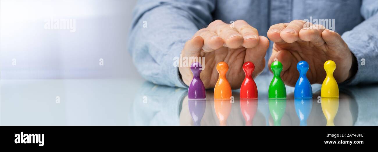 Gros Plan Sur La Main D'Une Personne Protégeant Les Pions Multicolores Sur Le Bureau Banque D'Images