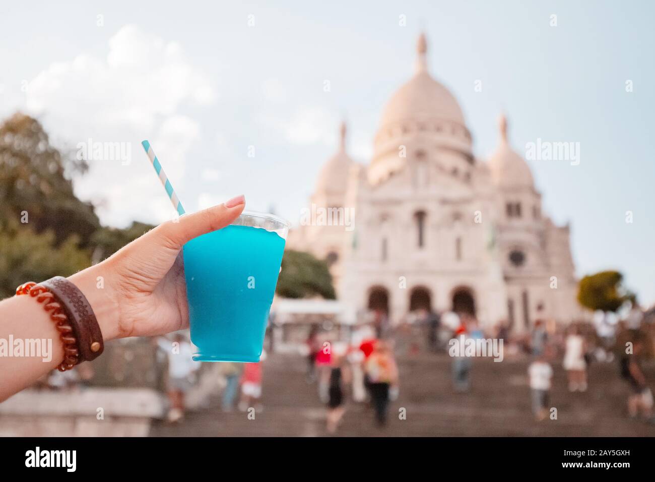 Une fille photographie une tasse de cocktail bleu sur le fond de la basilique du cœur sacré de Montmartre à Paris Banque D'Images