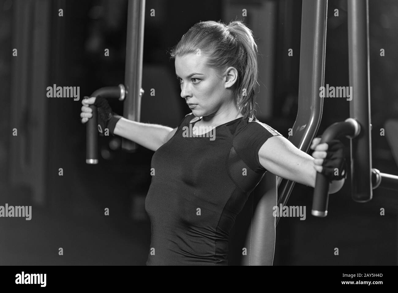 Femme à la salle de sport sport faire des exercices d'armes sur une machine Banque D'Images