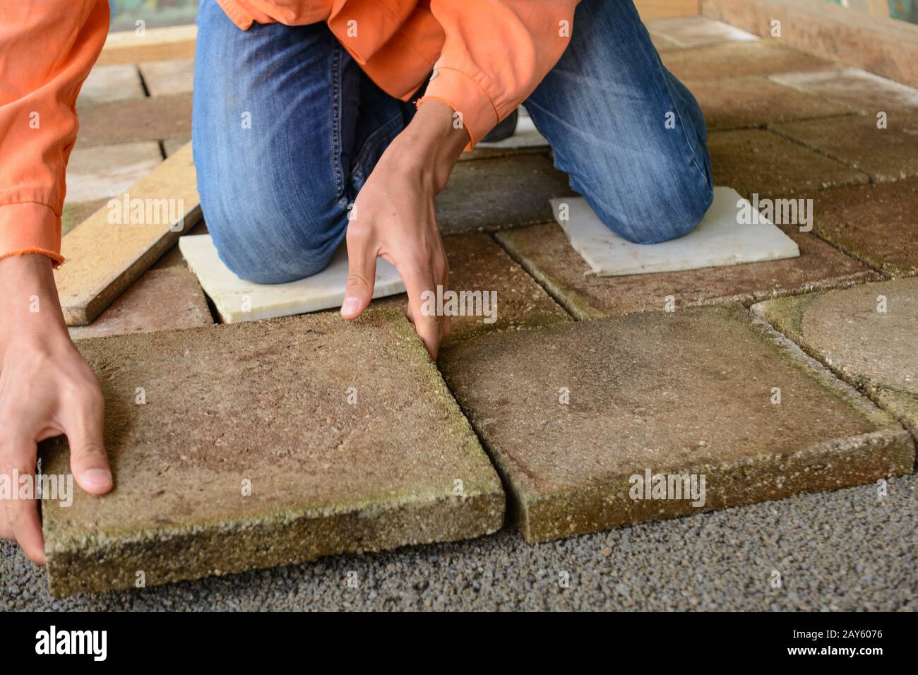 Un travailleur qualifié pave le sol avec des dalles de pierre Banque D'Images