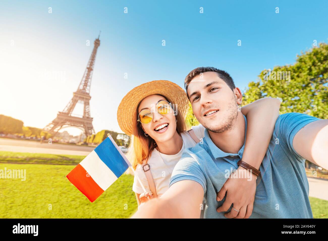 Couple mixte de course amoureux embrassant et prenant selfie avec drapeau français et tour Eiffel en arrière-plan. Voyage de lune de miel en France et Paris concept Banque D'Images