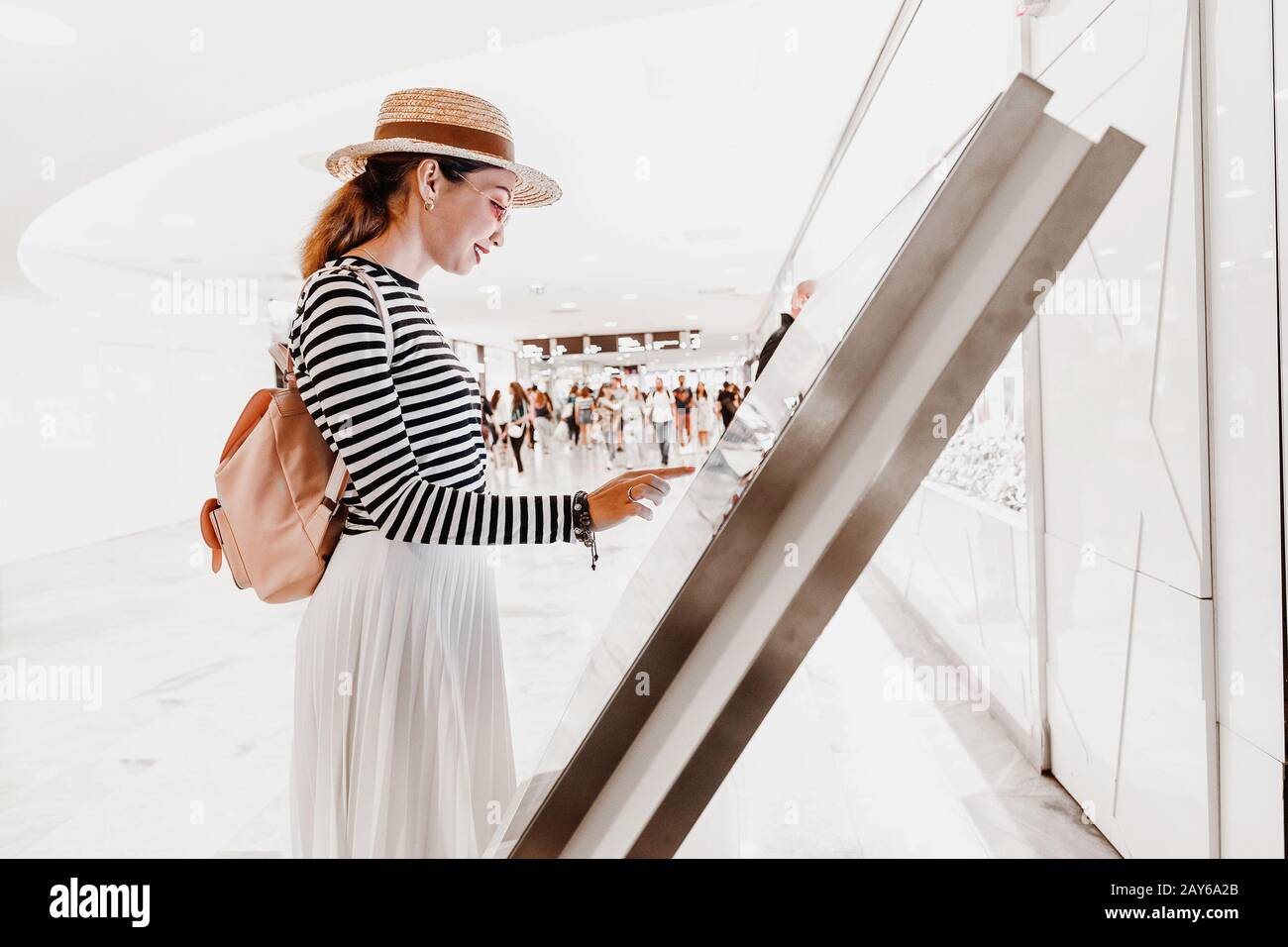 Asian girl utilise un terminal tactile pour trouver la boutique appropriée dans un grand centre commercial Banque D'Images