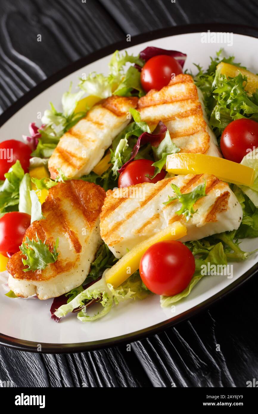Salade méditerranéenne au fromage hallumi grillé avec tomates, poivrons et laitue qui se ferme sur la plaque de la table. Verticale Banque D'Images
