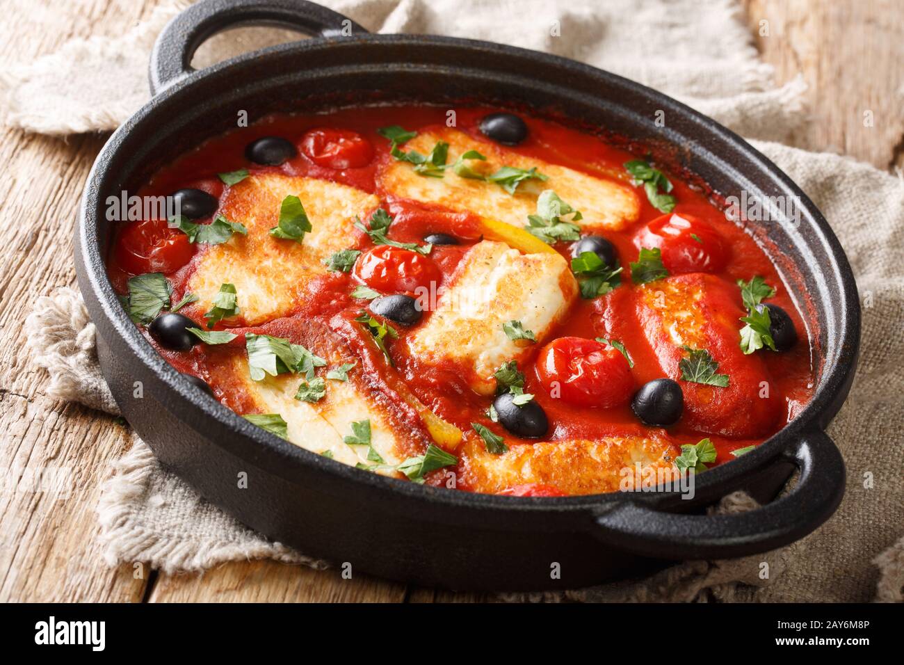 Fromage Halloumi traditionnel avec tomates, poivrons, olives dans une sauce épicée dans une poêle sur la table. Horizontale Banque D'Images