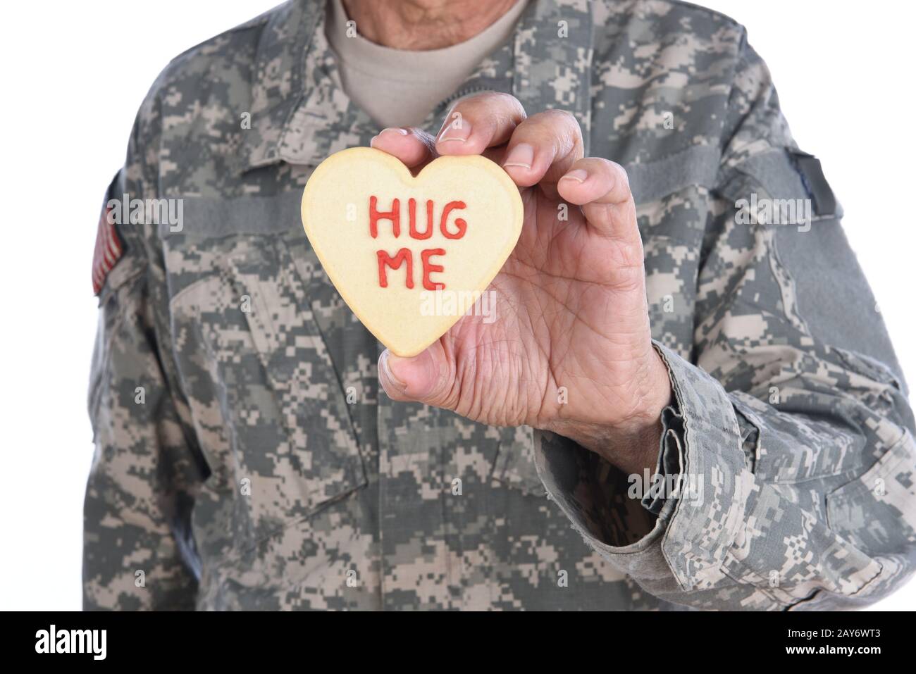 Gros plan d'un soldat tenant un cookie de Saint-Valentin en forme de coeur avec les mots Hug Me écrits en givrage rouge. Banque D'Images