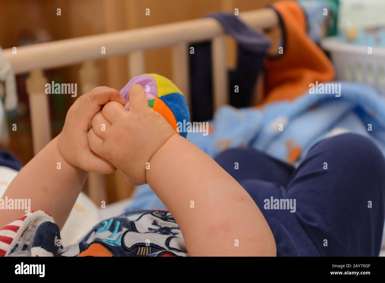 Bébé jouant dans un lit de bébé avec un petit softball - gros plan Banque D'Images