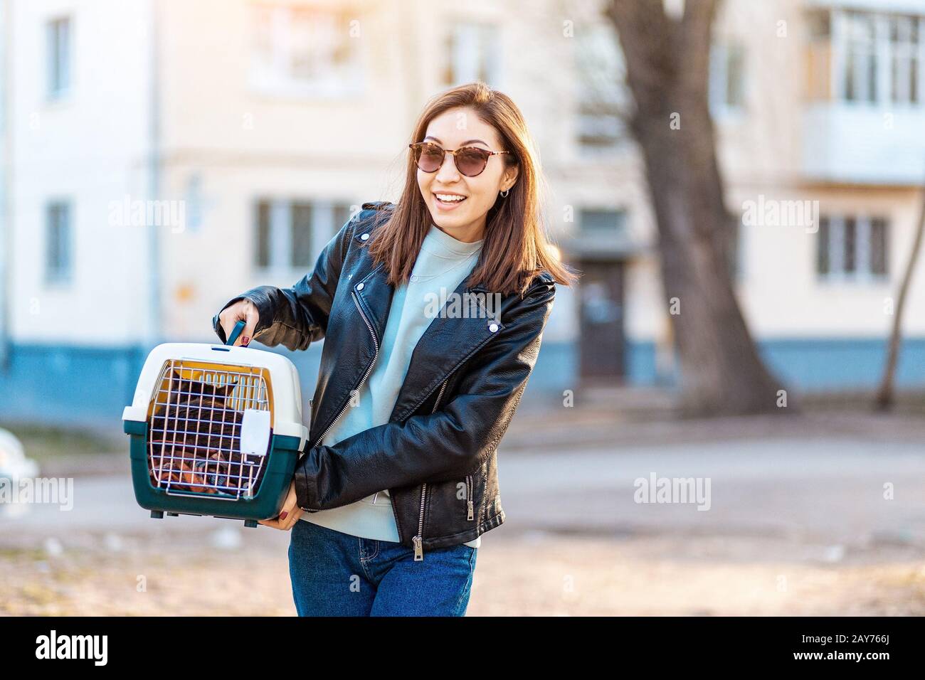 La propriétaire d'animal de compagnie de fille porte son chat dans un support spécial de cage en plastique pour une promenade ou dans une clinique vétérinaire Banque D'Images