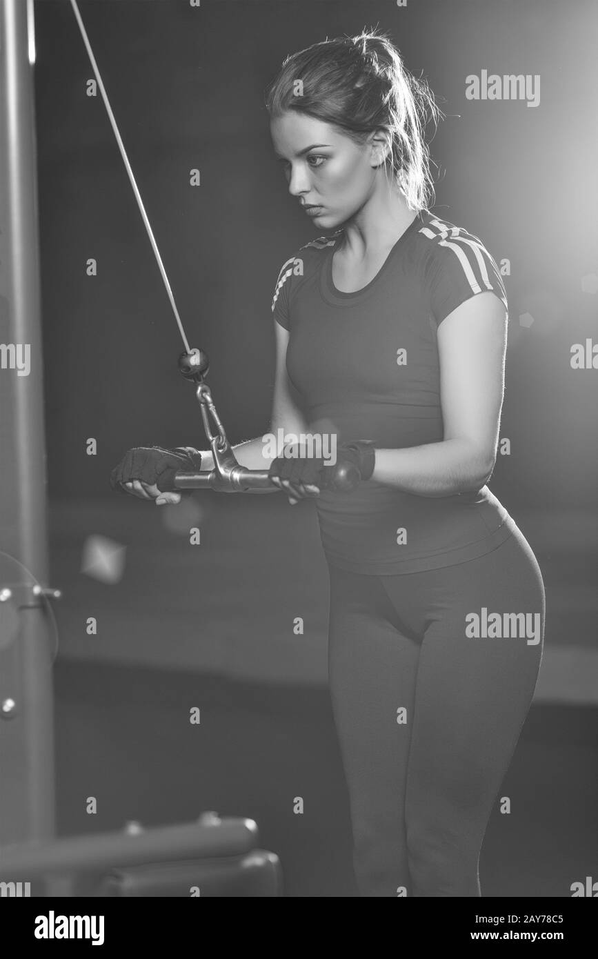 Femme à la salle de sport sport faire des exercices d'armes sur une machine Banque D'Images
