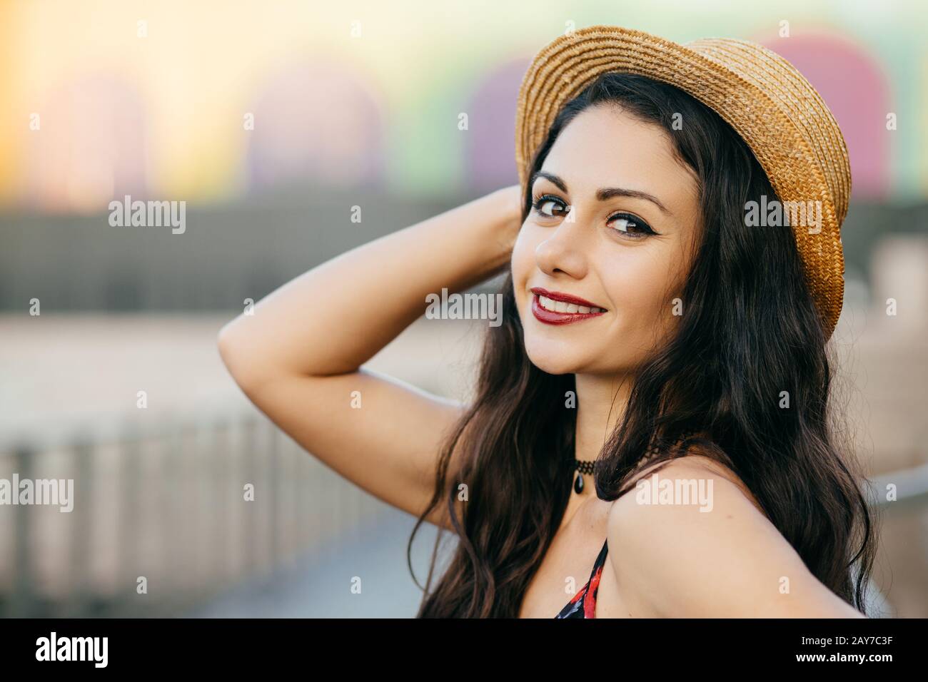 Portrait latéral d'une femme brunette aux yeux sombres, lèvres rouges et peau pure saine portant un chapeau de paille souriant agréablement à l'appareil photo ayant Happy expres Banque D'Images