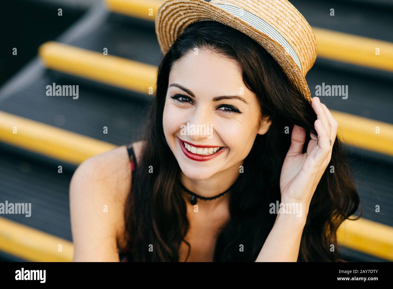 Gros portrait d'une femme gaie avec des cheveux sombres, des yeux pleins de bonheur et des lèvres minces portant un chapeau de paille, en gardant la main dessus, se sentant excité après Banque D'Images