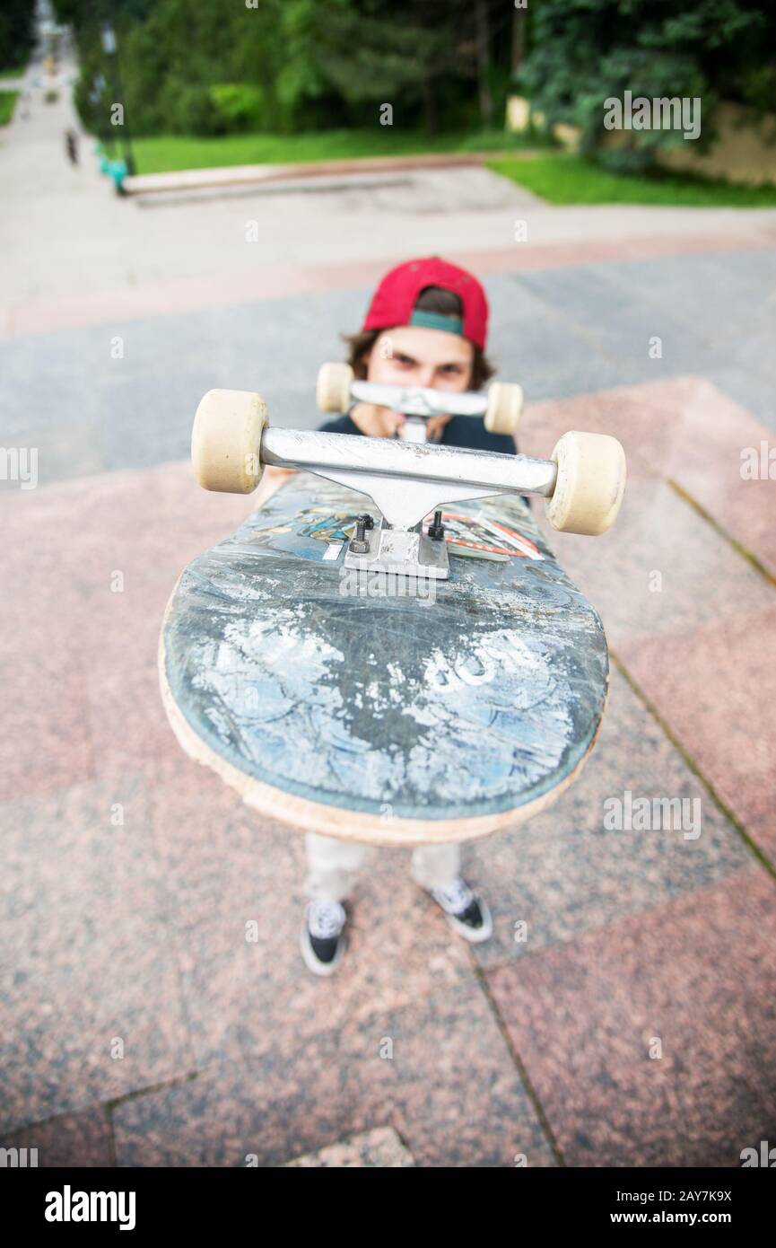 Un jeune patineur se tient avec un skateboard sur l'arrière-plan du paysage de la ville Banque D'Images