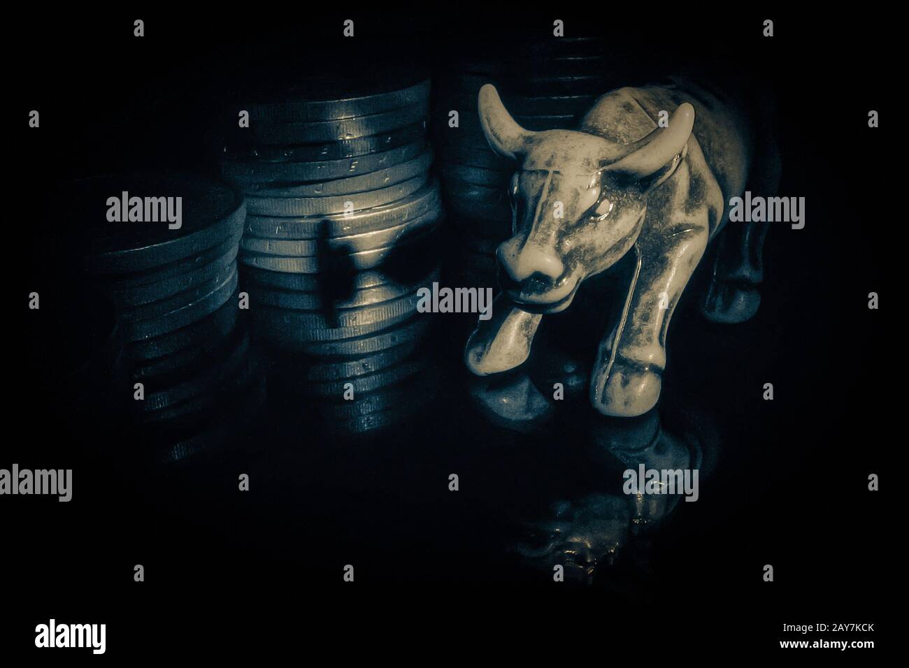 Figurine Bull sur une surface réfléchissante noire sur un fond de pièces.Le symbole de la tendance à la hausse.Market.Forex. Banque D'Images